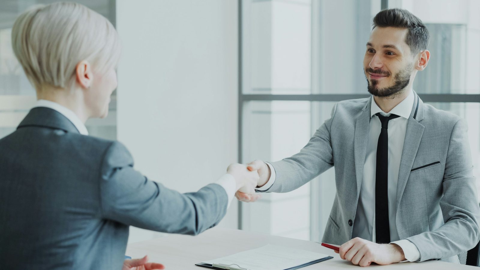 A hiring manager shaking hands with a candidate after a successful interview