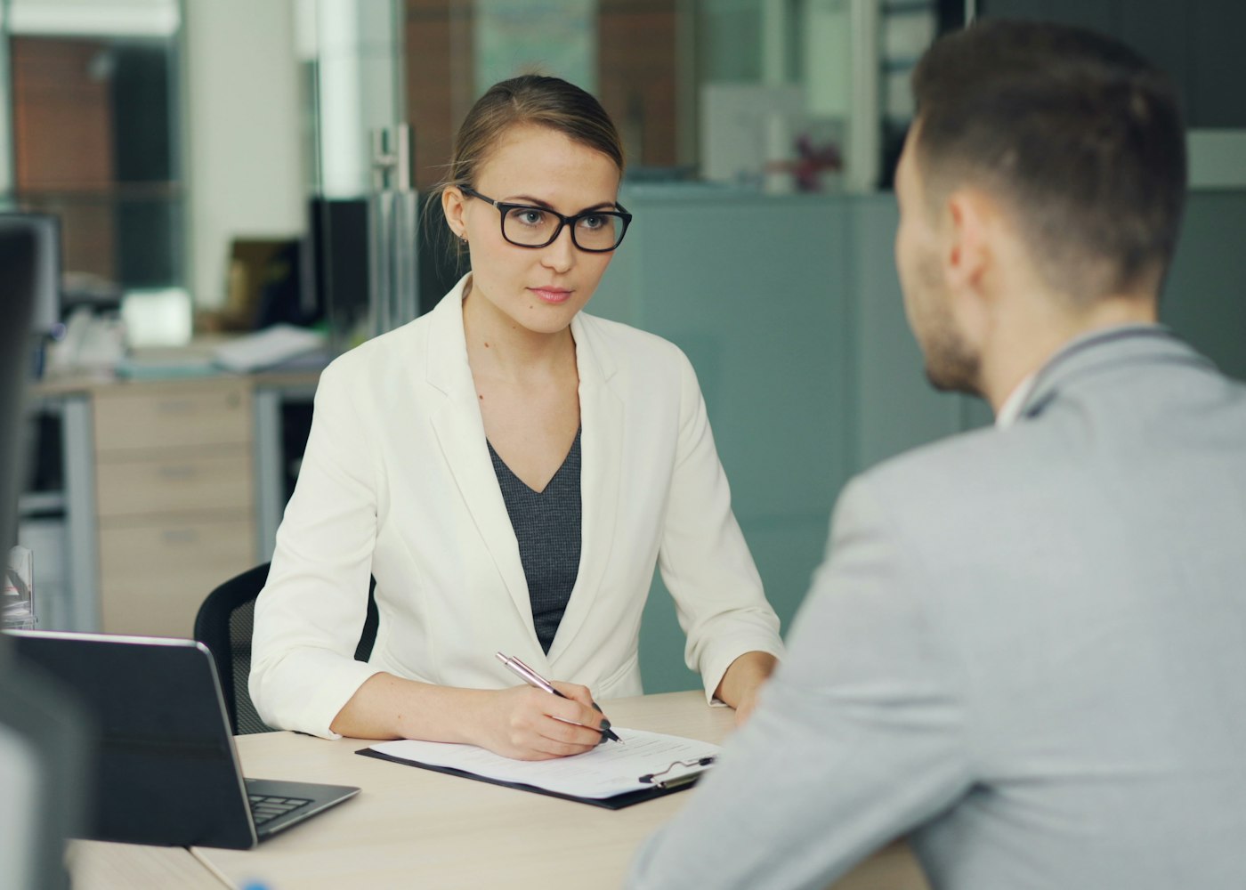 A hiring manager interviewing a finance candidate at an office desk